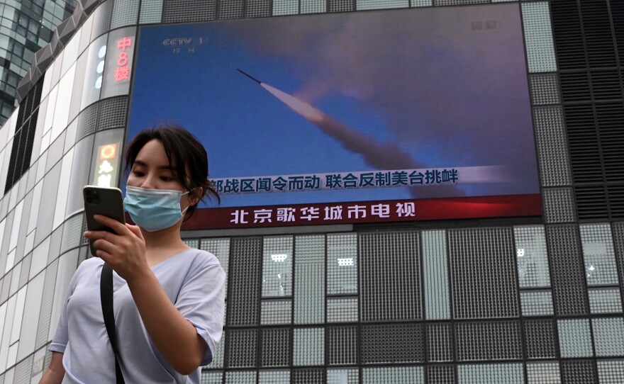 A large screen shows a news broadcast about China's military exercises encircling Taiwan, in Beijing in 2022.