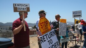 Protesters hold signs along a road in Murrieta, July 1, 2014.