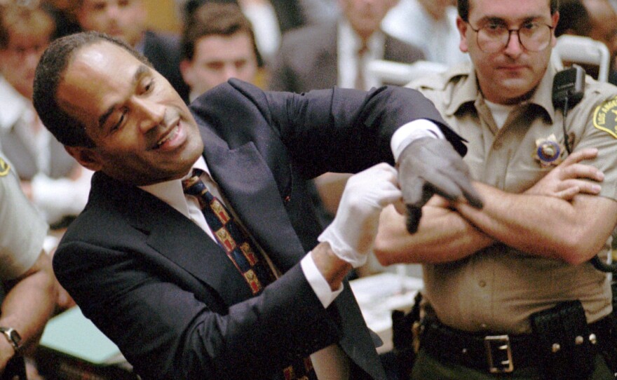 FILE - In this June 15, 1995 file photo, O.J. Simpson, left, grimaces as he tries on one of the leather gloves prosecutors say he wore the night his ex-wife Nicole Brown Simpson and Ron Goldman were murdered in a Los Angeles courtroom.