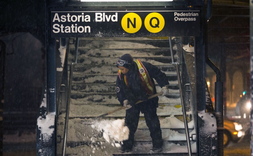 A worker clears snow from a stairway at the Astoria Blvd subway station in Queens, N.Y. New York City public schools were closed Friday after up to seven inches of snow fell during the first local snowstorm of the winter.