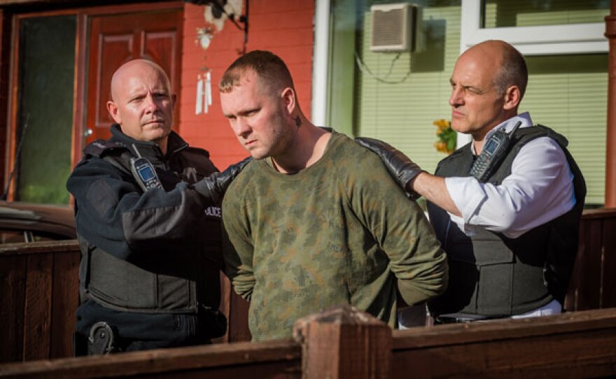 DC Ian Mitchell (David Prosho) walks out of the house with Ben Townsley (James Lewis) arrested.