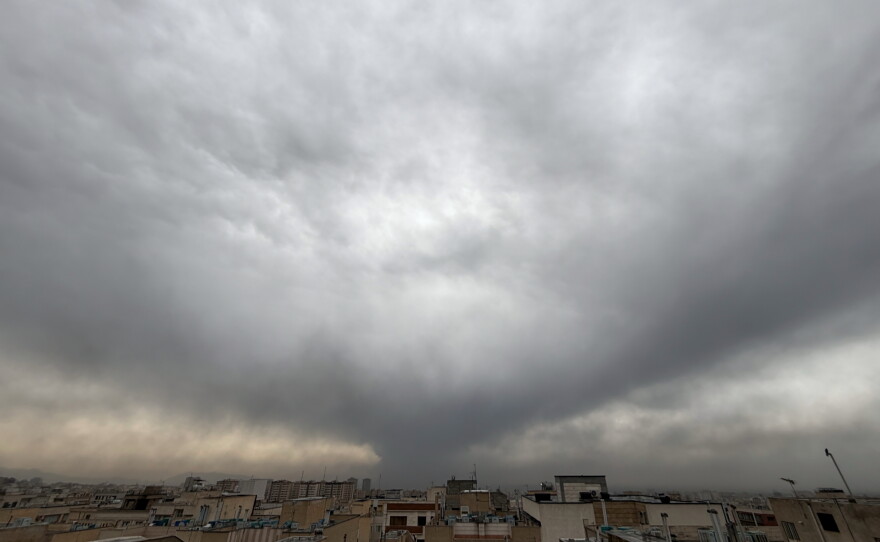Plumes of smoke from a U.S.-Israeli strike on an oil facility late Saturday linger and merge with the cloudy sky over Tehran, Iran, Sunday.
