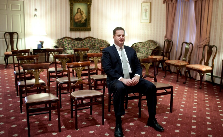 Funeral director Bob Lawler sits alone in a visitation room with the casket of Nicholas Miller as he waits for students from Roxbury Latin school to arrive and act as pallbearers for the burial.