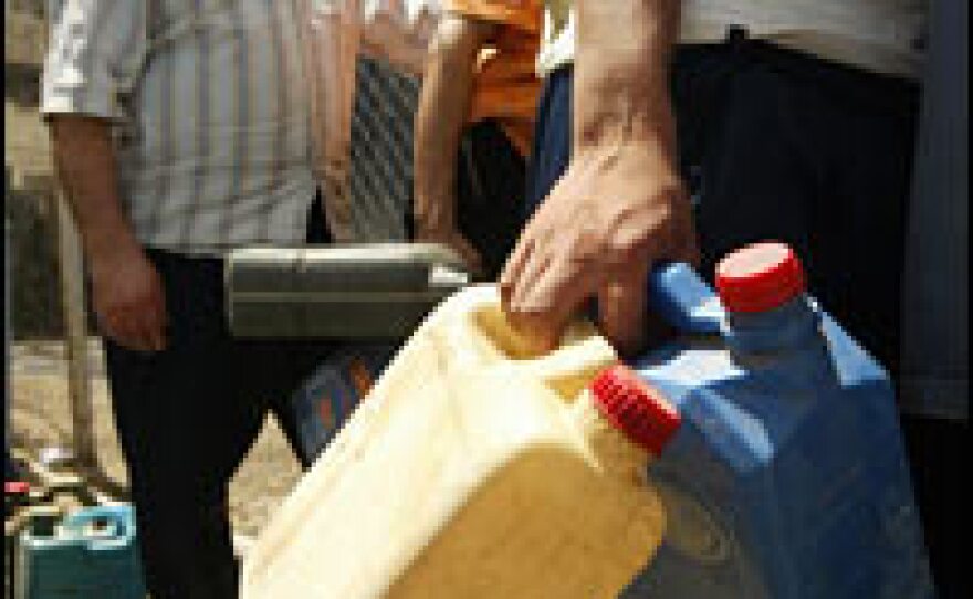 Iraqis in Baghdad line up to fill plastic containers with gasoline for their home generators.
