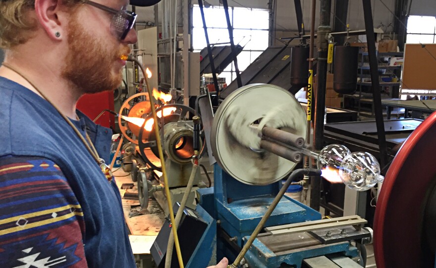 Neil Messinger, 23, a second-year student in Salem Community College's scientific glass technology program, uses a glass lathe to turn a bottle in Alloway, NJ.