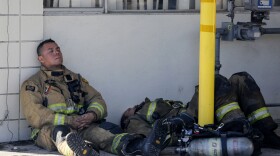 Firefighters rest at outside a cardboard box factory that burned down by a wildfire in Riverside, Calif. Thursday, Oct. 31, 2019. 
