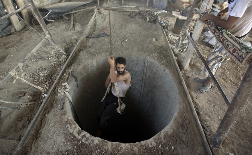 A Palestinian man is lowered into a smuggling tunnel that runs beneath the Egypt-Gaza Strip border, on Sept. 11, 2013. For the past year, Egyptian forces have cracked down on smuggling tunnels which Gazans used to import a wide range of goods, including weapons.