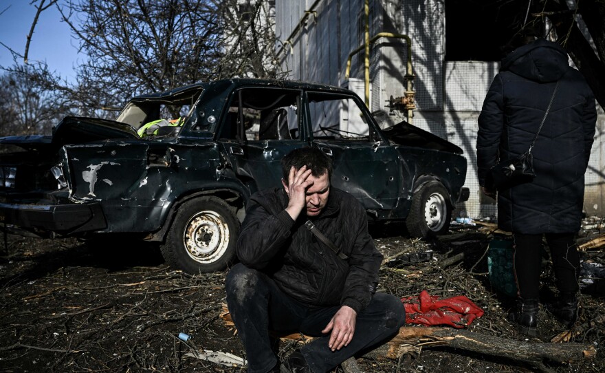 A man sits outside his destroyed building after bombings on the eastern Ukraine town of Chuguiv on Feb. 24, 2022.