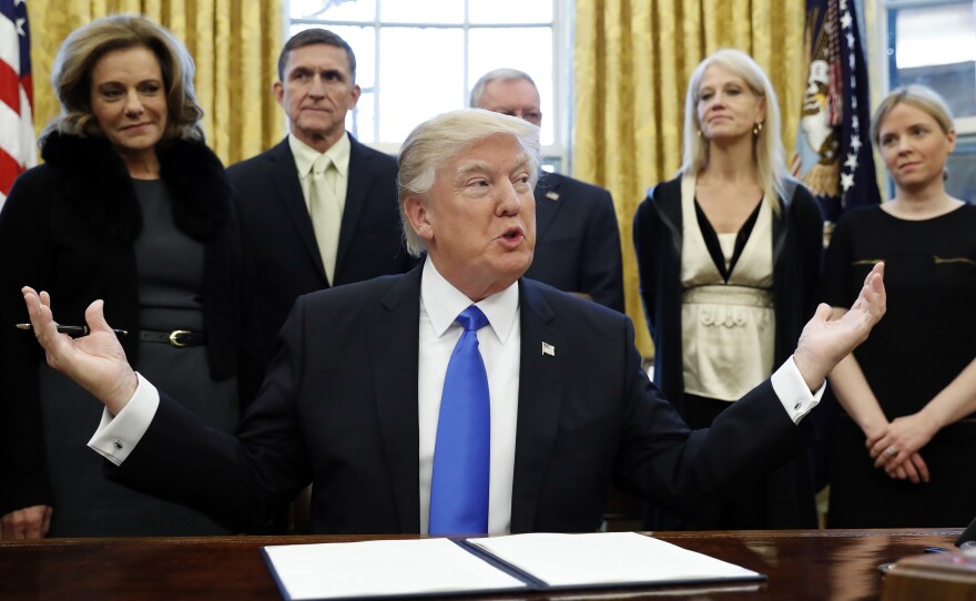 President Trump pauses before signing one of three executive actions in the Oval Office, Saturday.