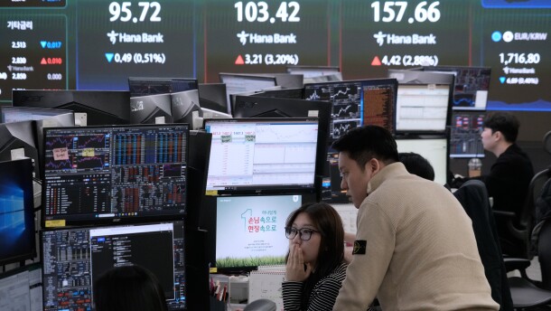 Currency traders watch monitors near a screen showing international oil prices at the foreign exchange dealing room of the Hana Bank headquarters in Seoul, South Korea, on March 18.