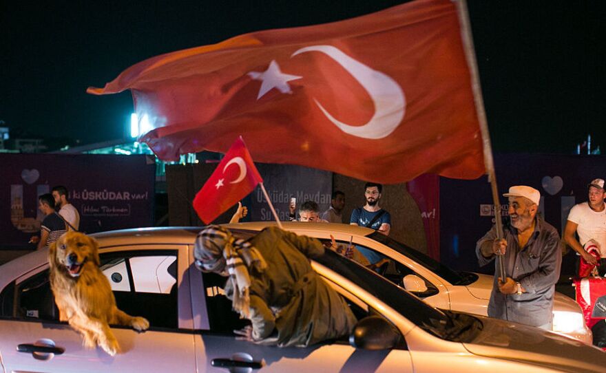 People drive next to a Turkish man waving a flag in Uskudar district in Istanbul on July 16, 2016 during a demonstration in support to Turkish president.