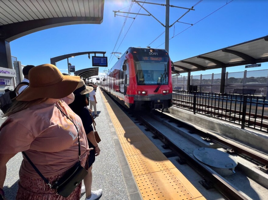People wait to board the trolley at the Nobel Drive Trolley Station in La Jolla, Calif. Nov. 21, 2021.