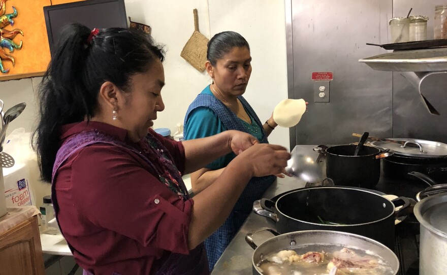 Rosa Hernandez prepares chicken for mole, while Sylvia Rojas makes tortillas, in this undated photo.