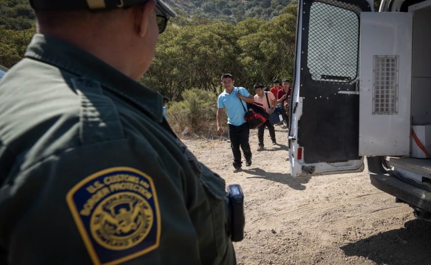 Un agente de la Patrulla Fronteriza conduce a un grupo de migrantes que buscan asilo hacia una camioneta para ser transportados y procesados, cerca de Dulzura el 5 de junio de 2024. Foto de Gregory Bull, AP Photo