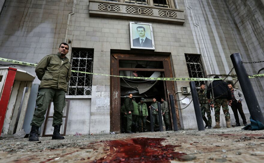 Syrian security forces gather under a portrait of President Bashar Assad at the Palace of Justice in Damascus following a suicide bombing on Wednesday.