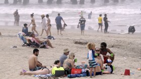 People sit on the beach Sunday, April 26, 2020, in Huntington Beach, Calif. 