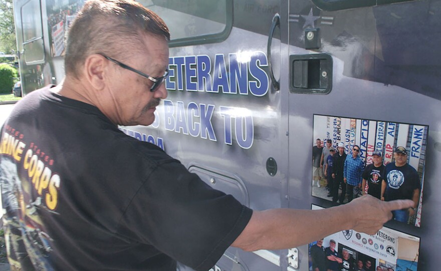 Manuel Valenzuela pointing out photos of deported veterans on the side of his RV