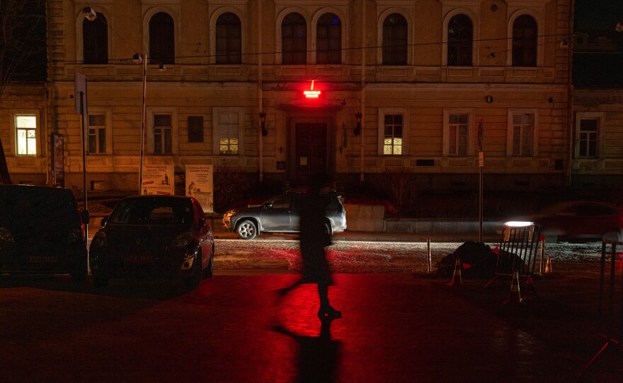 A woman walks through darkened Kyiv as many street lights remain off due to power shortages in the capital after numerous Russian air strikes on the country's energy infrastructure on Friday in Kyiv, Ukraine.