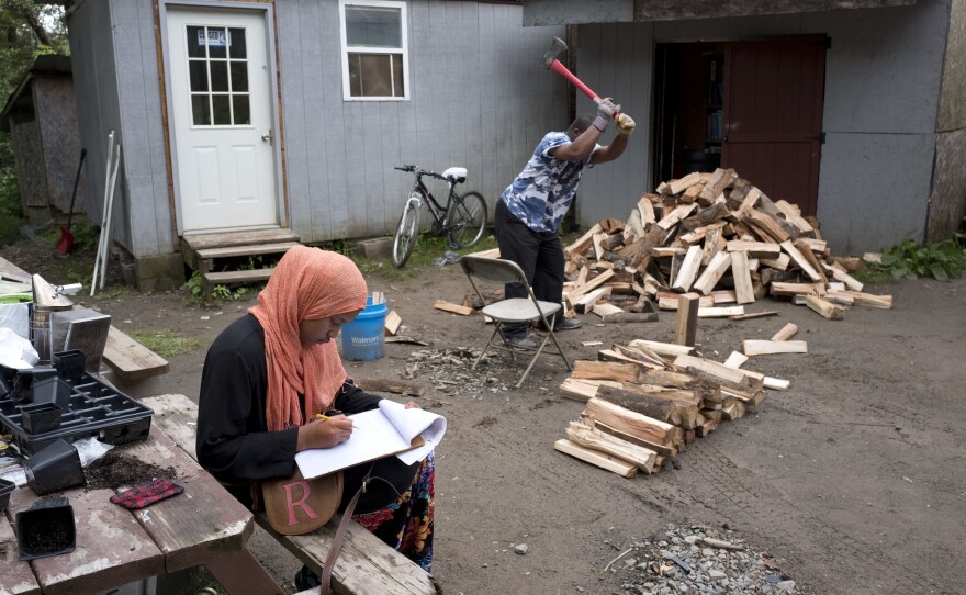 Seen in 2017, a girl studies for school while a man chops wood in the Muslim enclave of Islamberg in Tompkins, N.Y. Four people have been arrested in an alleged plot to attack the community.