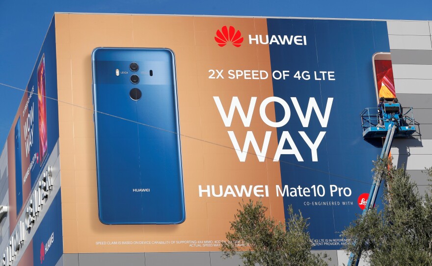 A crew hangs a Huawei advertising banner on the side of the Las Vegas Convention Center in January. Some senators want to ban it the world's third-largest seller of smartphones from the U.S.