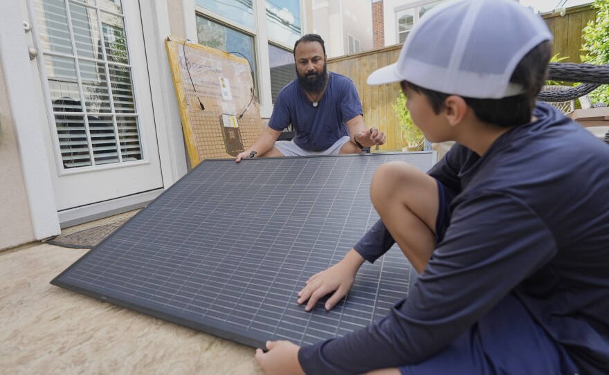 Bhavin Misra and his son, Rumi, attach a solar panel while assembling a plug-in solar kit at their home in Houston.