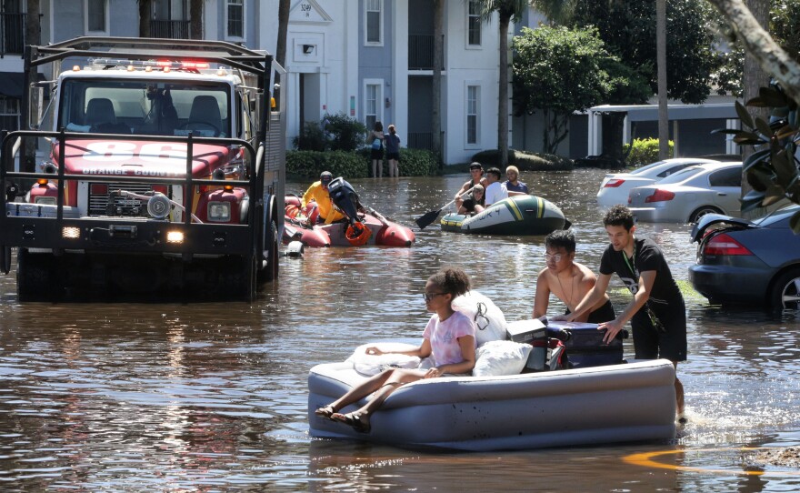 Residents escape from flooded homes in September 2022, after heavy rains from Hurricane Ian flooded an apartment complex near the University of Central Florida.