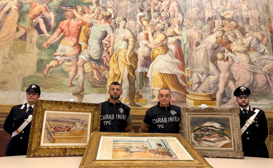 In this picture made available by the Italian Carabinieri in Parma, northern Italy, Friday, Aug. 14, 2026, Carabinieri pose near three artworks recovered following a police operation.