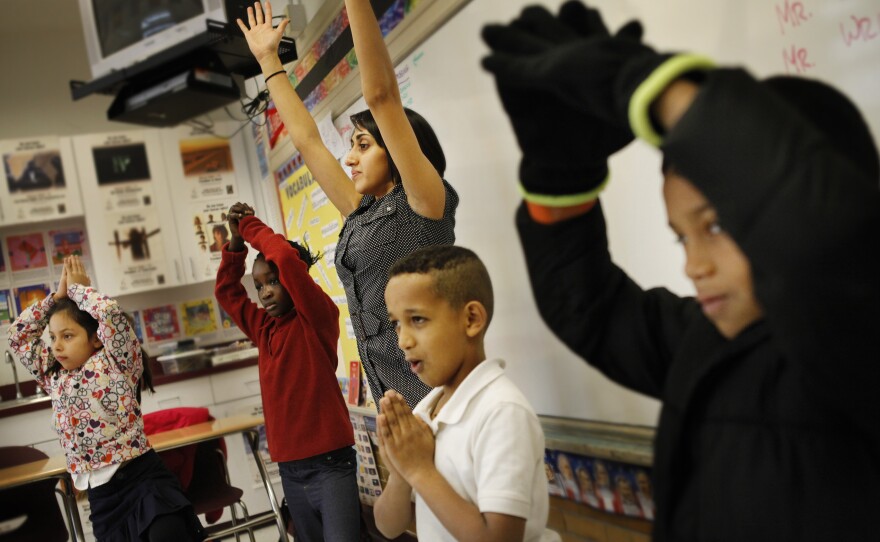Shah leads a group of third-graders in yoga poses during her peace class at Brightwood Education Campus in Washington, D.C.