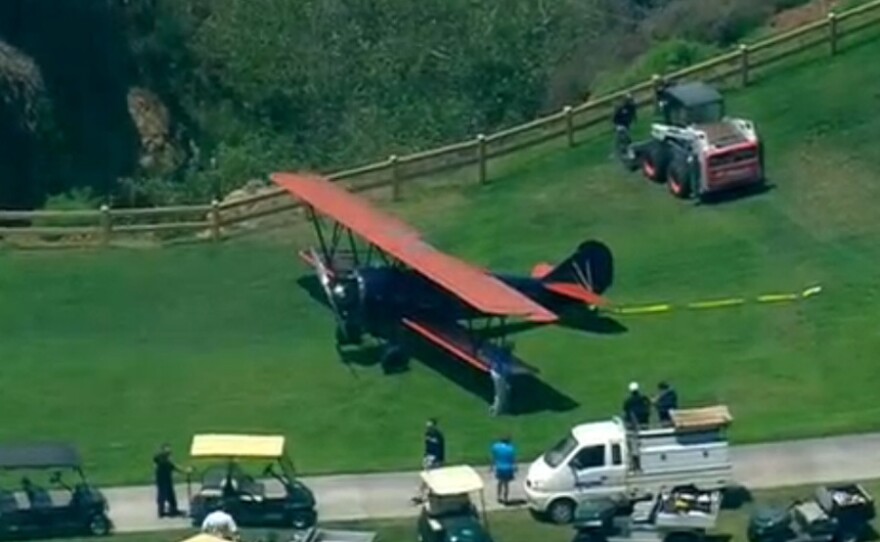 A vintage biplane is shown on the Torrey Pines Golf Course after making an emergency landing near the fourth hole, June 10, 2014.