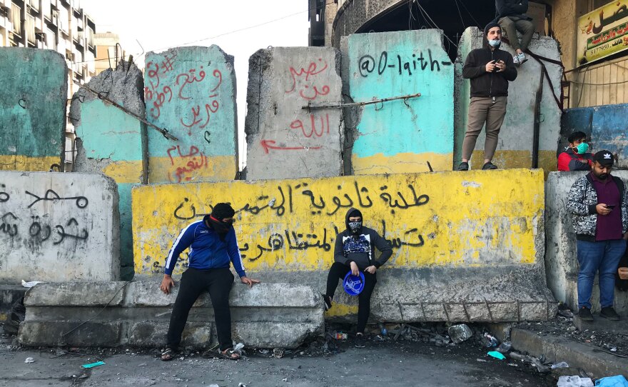 Protesters near Baghdad's Tahrir Square. The concrete barriers have been erected by security forces who are trying to prevent demonstrations from moving closer to Baghdad's fortified Green Zone.