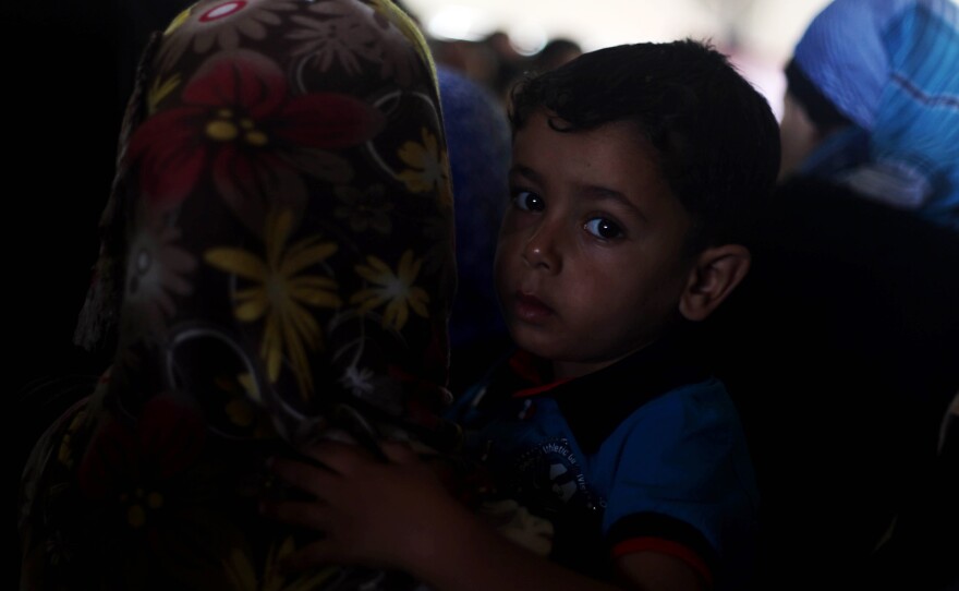 A Palestinian boy, hoping to cross into Egypt with his family, is held by his mother as they wait at the Rafah crossing between Egypt and the southern Gaza Strip on Tuesday. A cease-fire between Israel and Hamas held for a second day Tuesday as officials from both sides held indirect talks in Egypt.