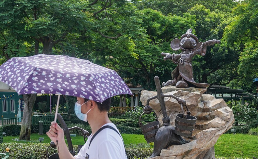 A visitor wearing a protective mask walking past a statue of Mickey Mouse at the Disneyland Resort in Hong Kong on the day it initially reopened, June 18. The amusement park will close again on Wednesday.