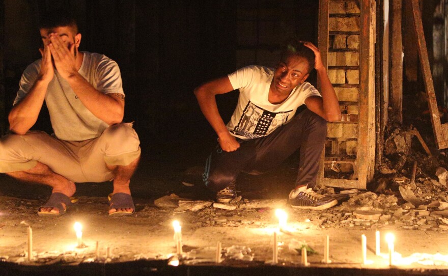 People light candles at the scene of a massive car bomb attack in Karada, a busy shopping district where people were shopping for the upcoming Eid al-Fitr holiday in central of Baghdad.
