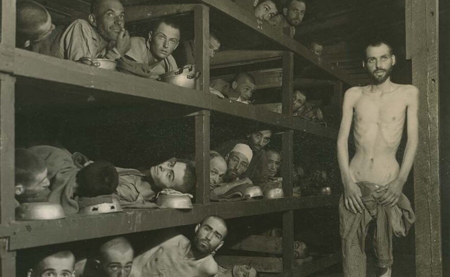 Former prisoners of the Buchenwald concentration camp are depicted in the wooden bunks where they slept. Elie Wiesel is pictured in the second row of berths, seventh from the left, next to the vertical beam.