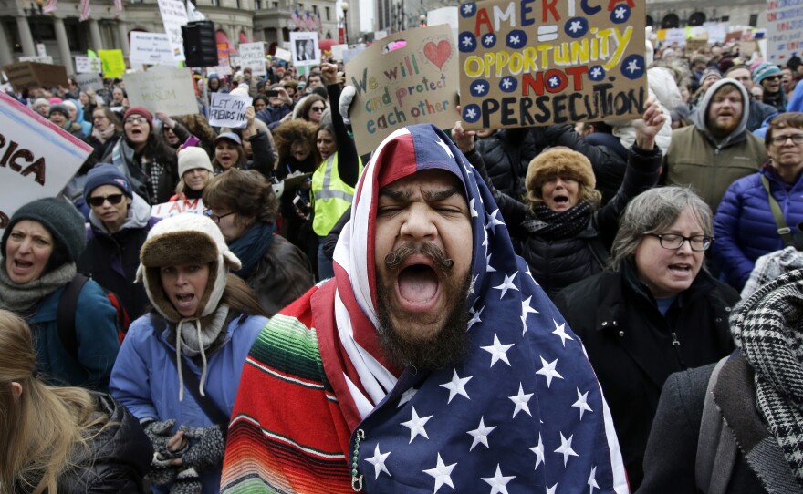Izzy Berdan (center) wears an American flag as he chants slogans with other demonstrators during a rally in Boston earlier today.