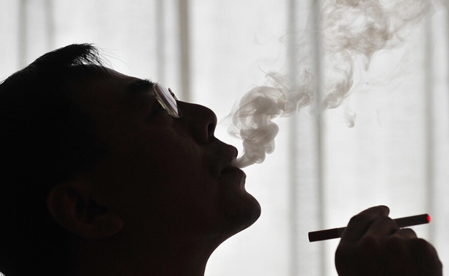 The inventor of the electronic cigarette, Hon Lik smokes his invention in Beiijng on May 25, 2009. Also known as an 'e-cigarette', the battery-powered device is designed as an alternative to cigarettes, cigars and pipes, and provides inhaled doses of nicotine by delivering a vaporized propylene glycol/nicotine solution, while also providing the physical sensation and flavors similar to inhaled tobacco smoke.