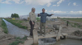RESOLVE TO SOLVE Host Miles O'Brien and farmer Reid Fishering walk the plank over the irrigation ditch, which is the lifeline for his sweet corn farm. (Delta, CO)