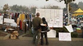 Tera Hickerson, right, and Columbus Holt embrace as they look at a board with information for services at a makeshift encampment outside a Walmart store for people displaced by the Camp Fire, Friday, Nov. 16, 2018, in Chico, Calif. 