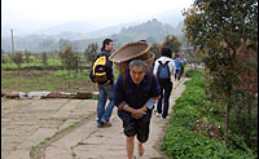 A Chinese peasant from the town walks past tourists, showing the juxtaposition of old and new.