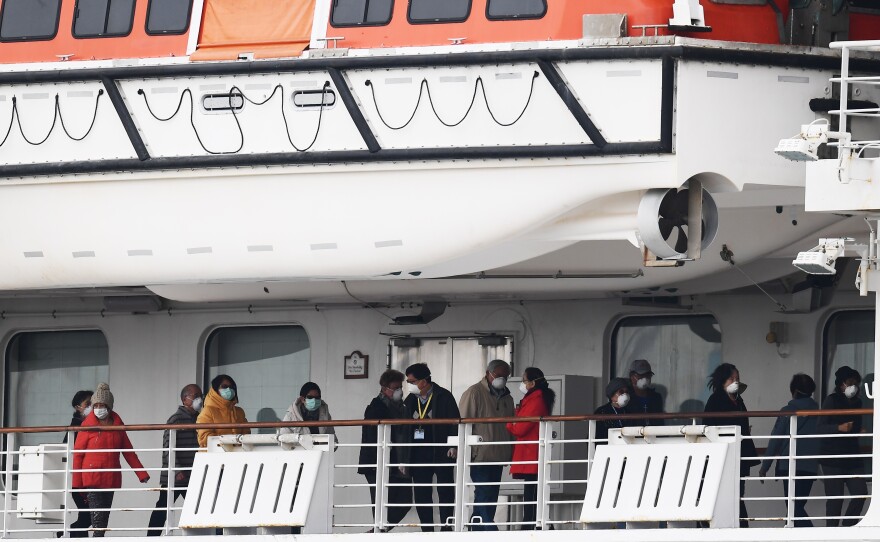 Passengers walk along the deck of the Diamond Princess cruise ship, on which about 3,600 people have been quarantined because of fears of the new COVID-19 coronavirus.