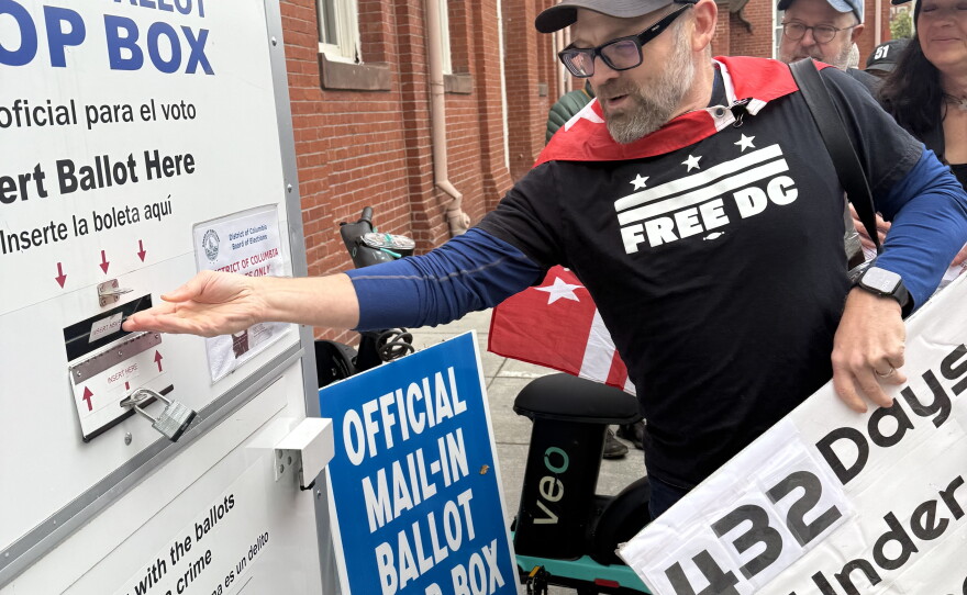 Chris Salm, a member of the Free DC group, puts his mail-in ballot in an official ballot drop box in Washington, D.C.
