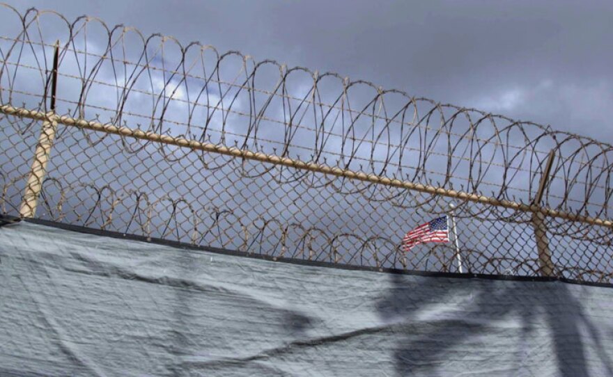 This photo shows an American flag inside Gitmo, seen through the barbed wire that surrounds the prison Guantanamo Bay, Cuba. In collaboration with NPR, "Out Of Gitmo" tells the dramatic story of a Gitmo detainee released from the controversial U.S. prison after 14 years, and the struggle over freeing prisoners once deemed international terrorists. A second segment with Retro Report explores the untold history of the Guantanamo Bay prison.