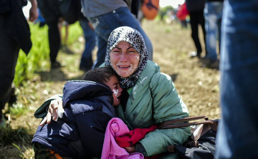 A woman and her children cry after being affected by tear gas near Idomeni on Sunday. Hundreds of people were hurt when police fired tear gas on a group of migrants as they tried to break through a fence on the Greece-Macedonia border, Doctors Without Borders said.