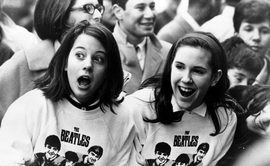 Two Beatles fans amongst a crowd of fans in New York, welcome the group as they arrive at the airport on Feb. 10, 1964. Music critics agree that the band wouldn't have been The Beatles we know without Martin.