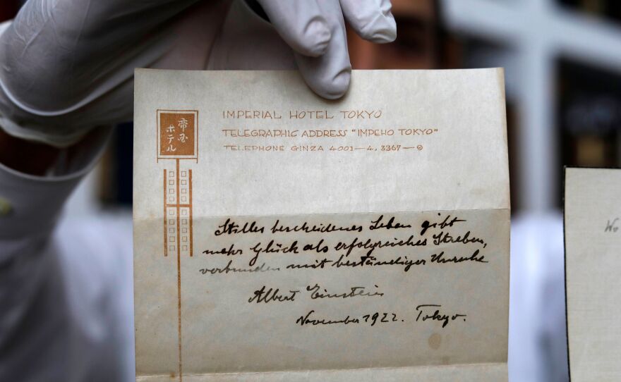 The owner of a Jerusalem auction house holds up a note on happiness written by Albert Einstein in 1922. The note, which Einstein gave to a courier in lieu of a tip, sold for $1.56 million on Tuesday to an anonymous buyer.