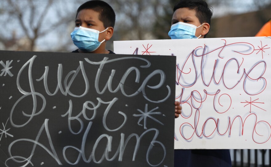 Two boys hold signs at an April 6 press conference, days after a Chicago police officer fatally shot 13-year-old Adam Toledo.