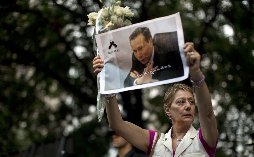 A woman holds up a portrait of late prosecutor Alberto Nisman near the funeral home where a private wake was held for him Wednesday in Buenos Aires.