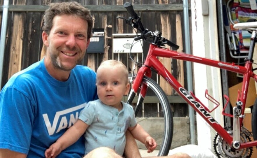 Matt Keenan sits with his son Evan in front of a red bike.