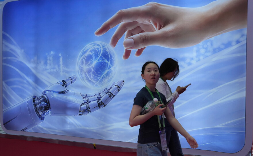 Visitors walk past a display depicting artificial intelligence and a human hand at the China International Supply Chain Expo in Beijing on June 22.