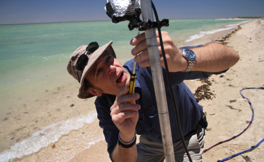 Mark Evans sets up a shark deterrent test on the beach.